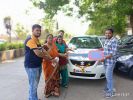 Three people standing by a parked car on a sunny day.