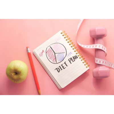 Diet plan with wieghts, pencil, apple, and measuring tape. We offer diet plan for weight loss.