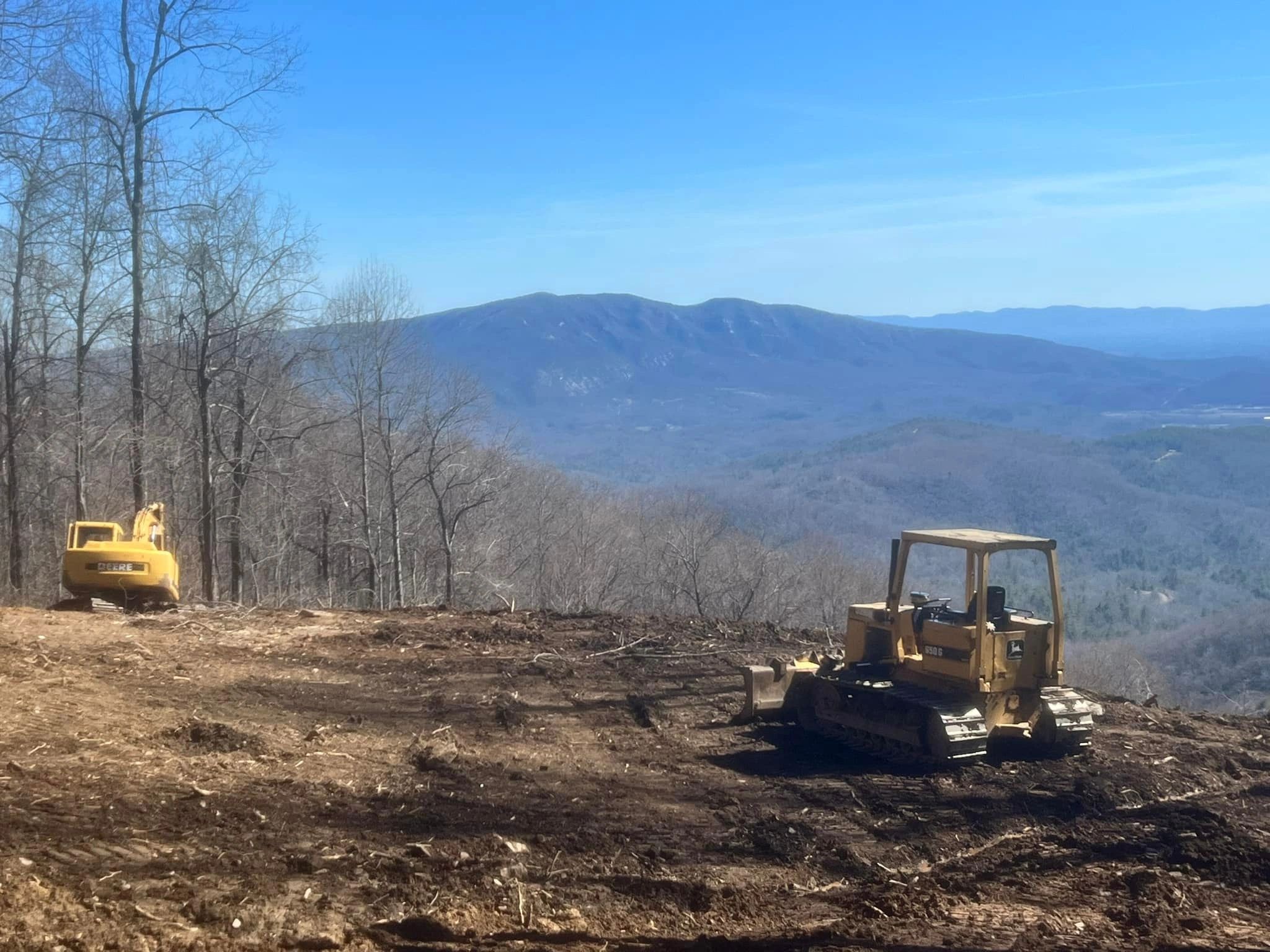 Construction vehicles at mountain clearing site.