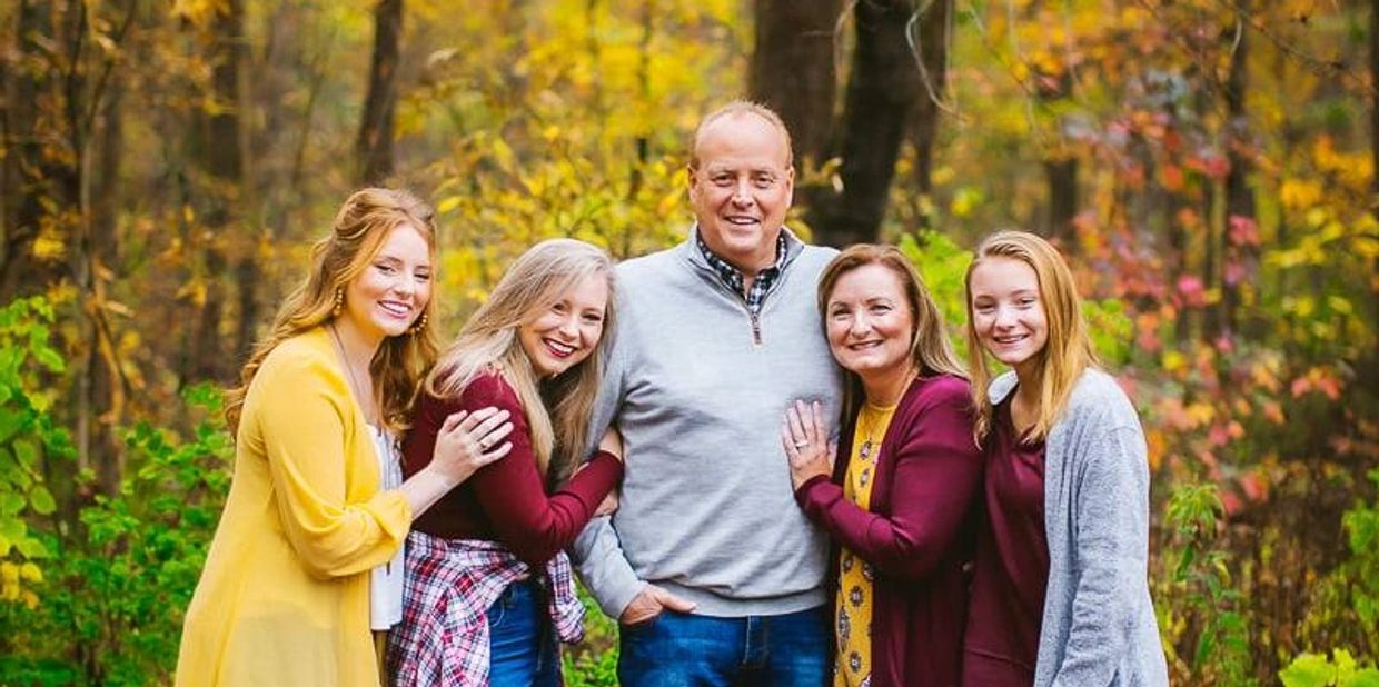 A smiling family posing outdoors during autumn.