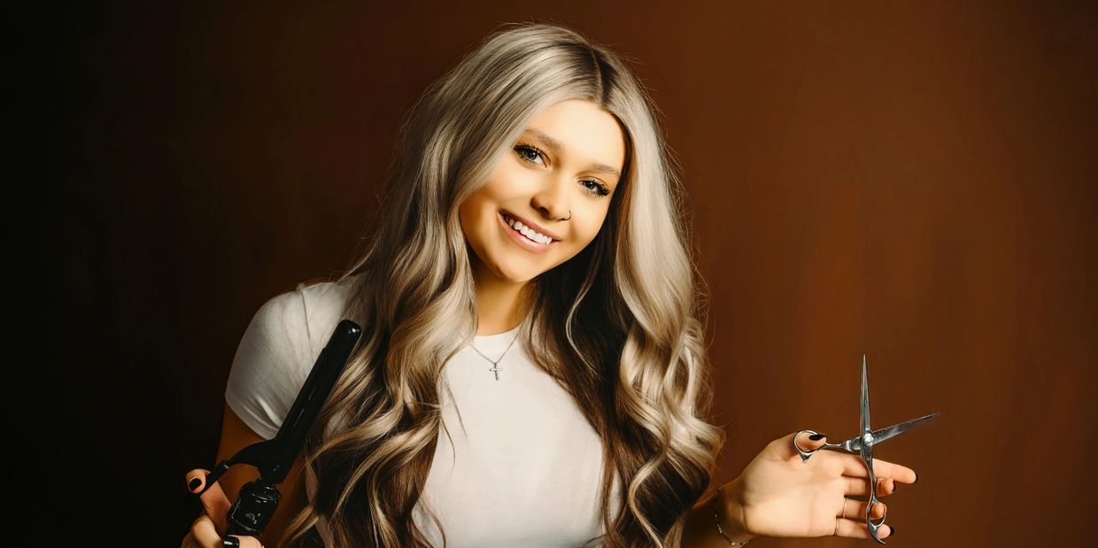 Smiling woman holding hair styling tools.