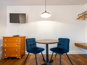 Small table and two blue chairs, wooden dresser and tv