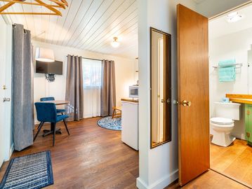 Interior view of cottage with small table with blue chairs, blue throw rugs and small bathroom
