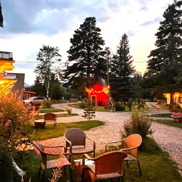 A little red cabin with twinkly lights surrounded by outdoor seating area