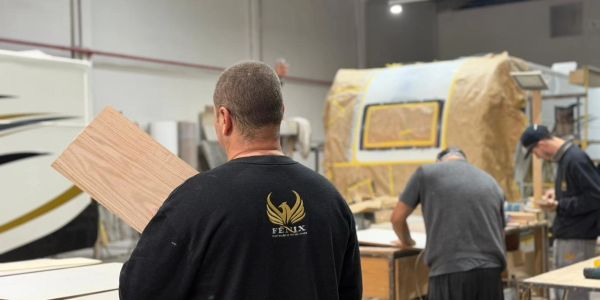 Workers crafting wood inside a workshop with a focus on a man holding a wooden plank.