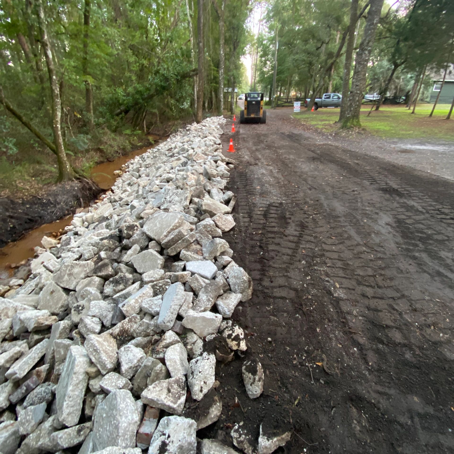 Construction work with rocks and machinery on a wooded path.