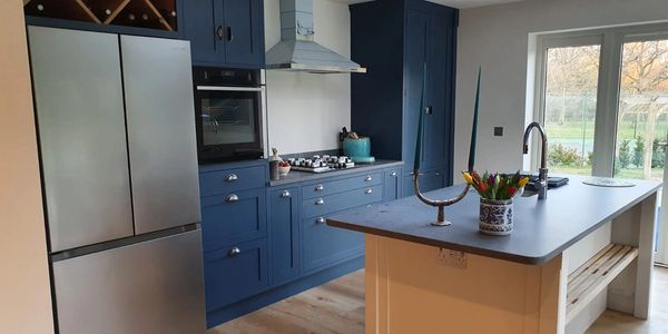 Modern kitchen with blue cabinets, stainless steel appliances, and an island with decorative items.