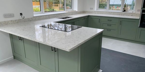 Modern kitchen with green cabinets and white marble countertops.