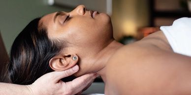 A woman laying supine (face up) receiving neck massage from Alexandria. Side profile angle.