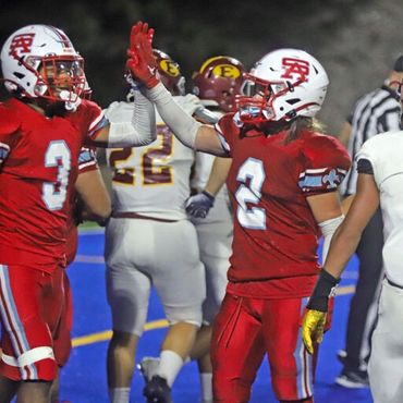 Santa Ana high school football players high fiving each other after game