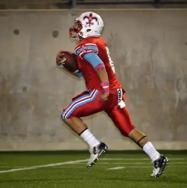 high school football player with ball running towards field goal