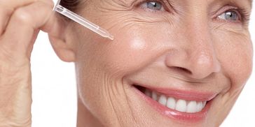 An older woman with a dropper of serum on her cheek