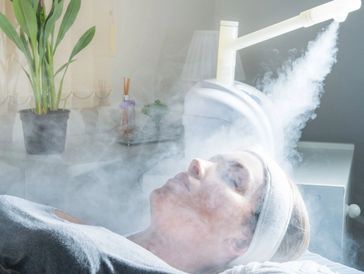 A woman laying down on a table with steam blowing in her face