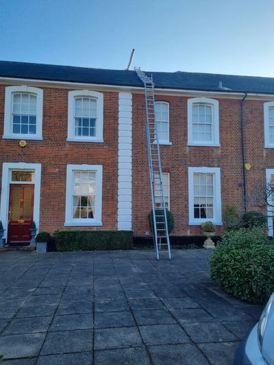 Ladder leaning against a brick house with a clear sky.