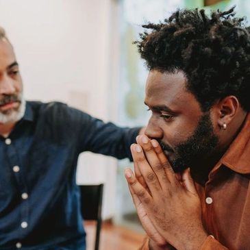 Man comforts another man deep in thought.