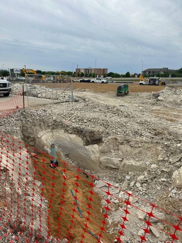 Construction site with excavation and machinery under cloudy sky.