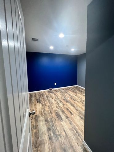 Empty room with wood flooring and blue accent wall.