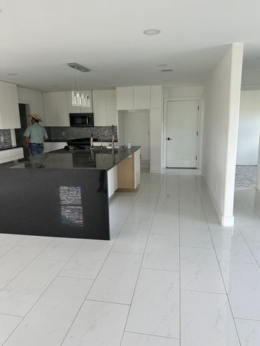 Modern kitchen with black granite island and white tile flooring.