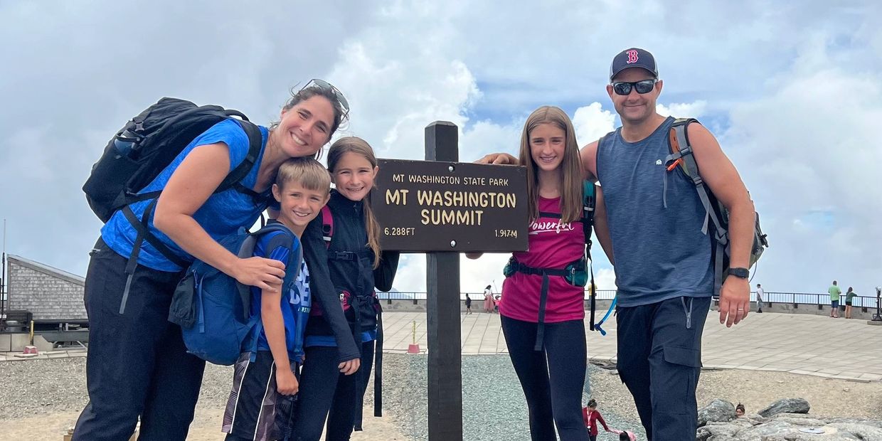 A family standing at the summit of the tallest mountain in New Hampshire - Mount Washington.