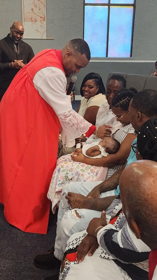 A pastor blesses a baby during a church ceremony.