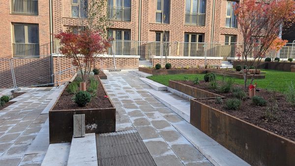 Modern garden with raised beds and autumn trees in front of brick apartments.