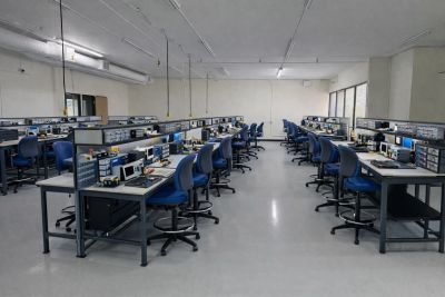 A spacious electronics lab with organized workstations and blue chairs.