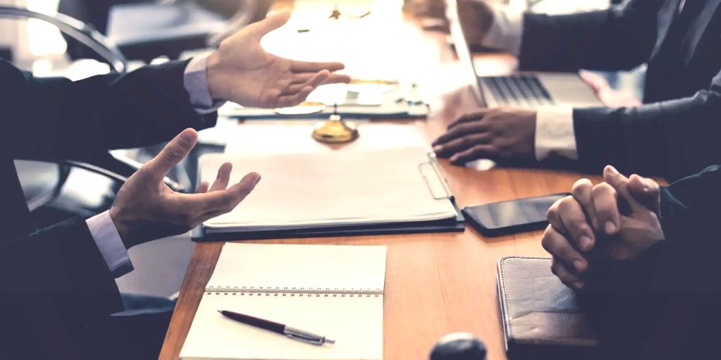 Business meeting with people discussing and taking notes at a conference table.
