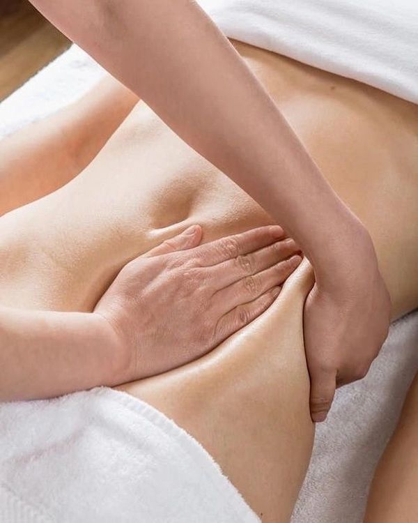 Massage therapist applying deep tissue massage to a person's lower back.