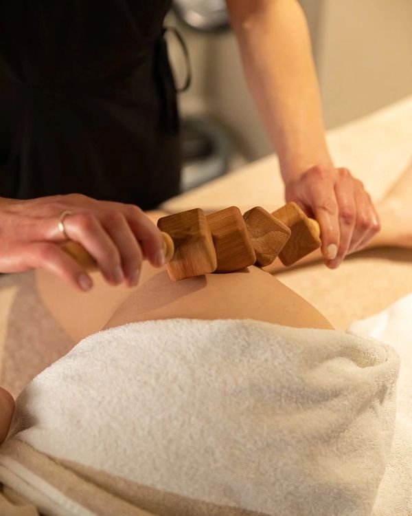 Person receiving a wooden massage roller treatment on their thigh.
