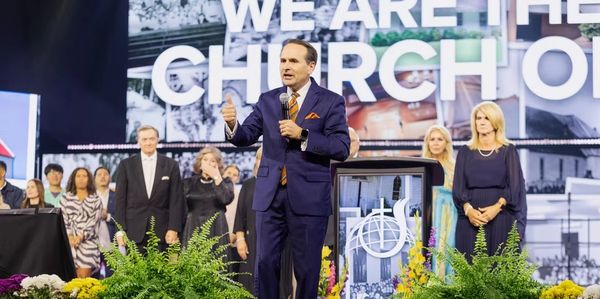 A man in a suit speaking on stage at a church event.