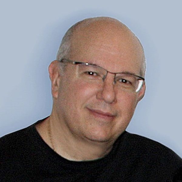 A smiling bald man wearing glasses and a black shirt.