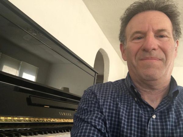 Man taking a selfie near a black Yamaha piano.
