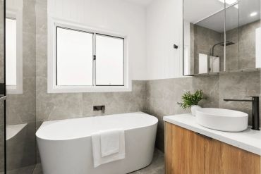 Modern bathroom with a white freestanding tub and wooden vanity.