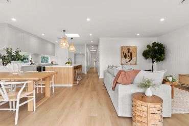 Bright, modern open-plan living room and kitchen with wooden accents and cozy decor.