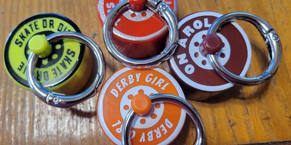 Colorful roller skate wheel keychains on a wooden surface.