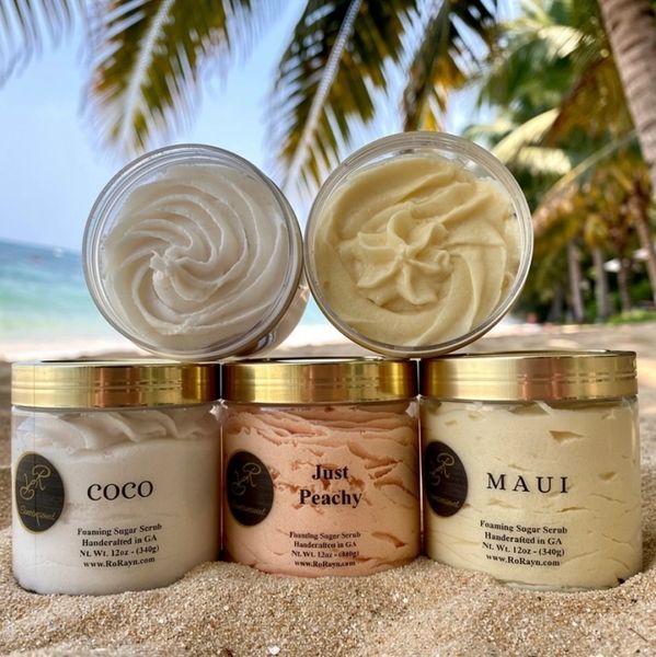 Three jars of foaming sugar scrub on a beach.