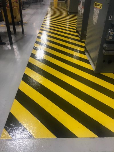 Yellow and black striped safety floor marking in an industrial setting.