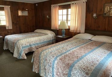 Cozy rustic bedroom with two beds and floral bedding under soft natural light.