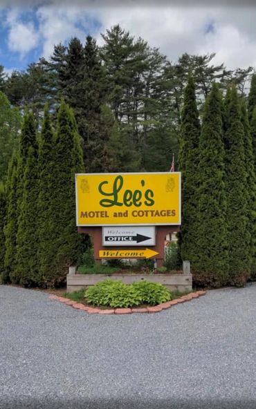 Sign for Lee's Motel and Cottages surrounded by tall greenery.