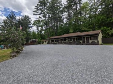 A quiet motel surrounded by tall trees under a cloudy sky.