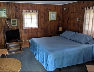 Cozy rustic bedroom with wood-paneled walls and blue bedding.