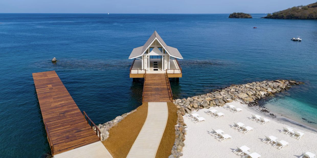 Pier with a pavilion extending into the ocean beside a sandy beach.