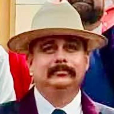 Man wearing a beige hat and a suit.