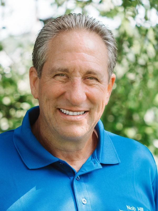 Smiling man in a blue polo shirt outdoors.