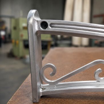 Close-up of a metal chair armrest with a spiral design.