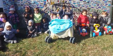 Group of children outdoors with colorful stroller and toys.