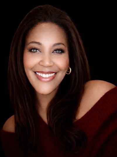 Smiling woman with long hair and gold hoop earrings.