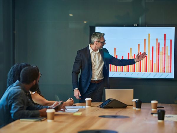 Man giving a presentation with a chart on a screen.