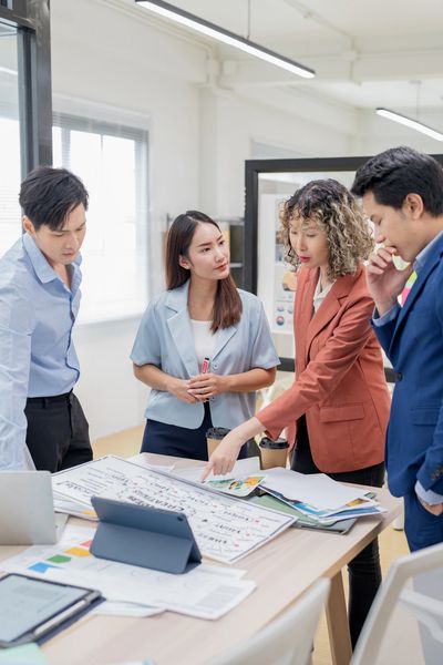 A team of business professionals collaborating around a table, reviewing charts.