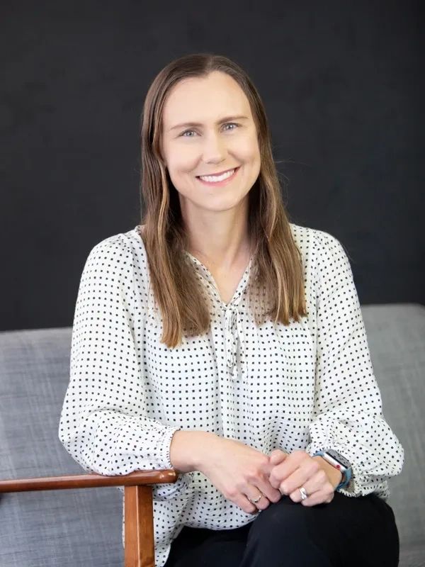 Woman in a polka dot blouse sitting and smiling.